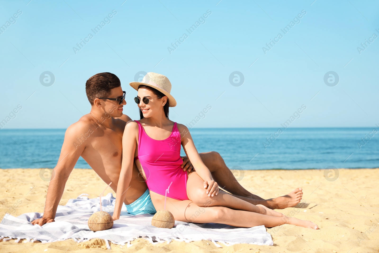 Photo of Happy couple resting on sunny beach at resort