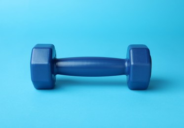 Photo of Stylish dumbbell on light blue background, closeup