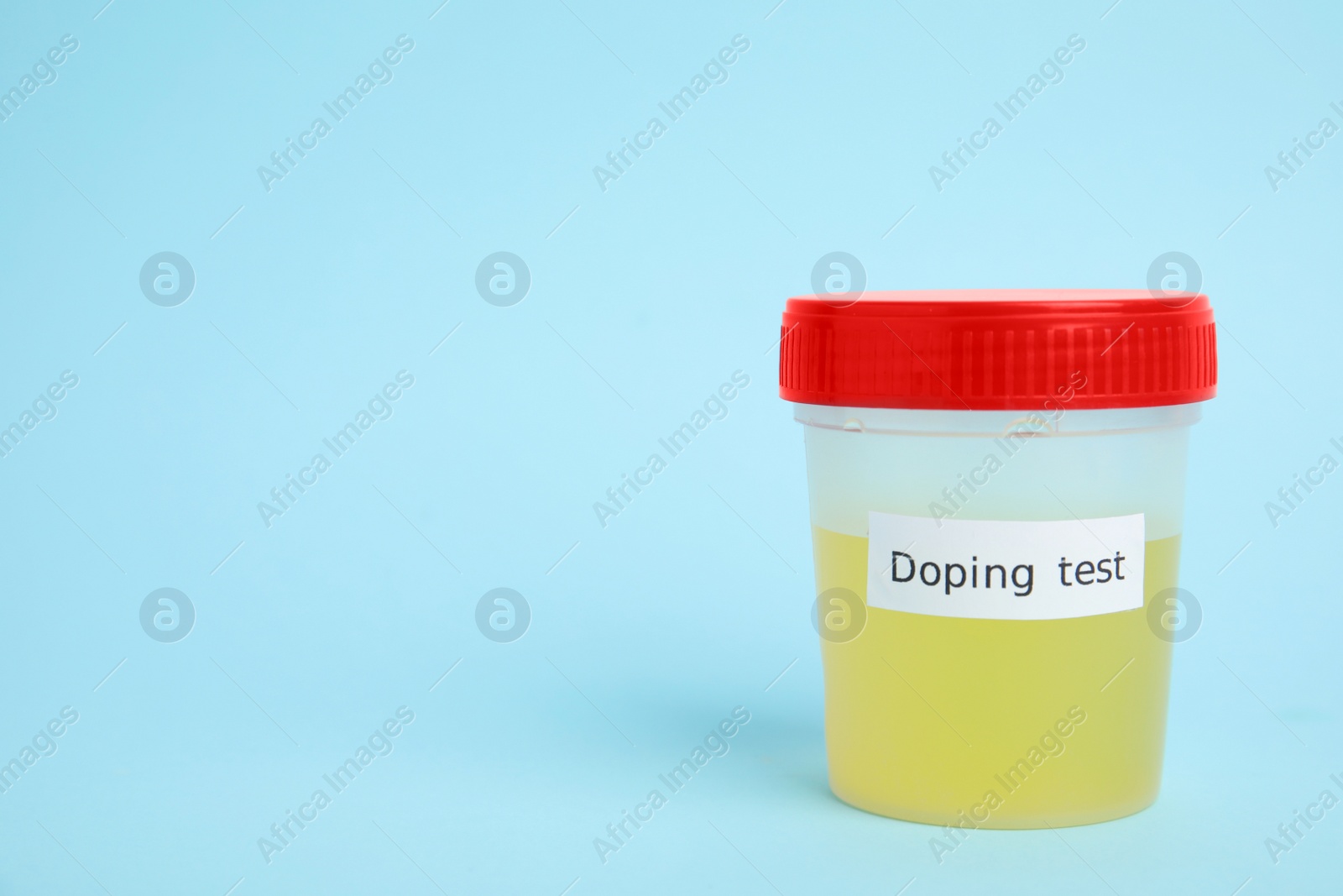Photo of Jar with urine sample on light blue background, space for text. Doping control