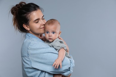 Beautiful mother with her cute baby on grey background. Space for text