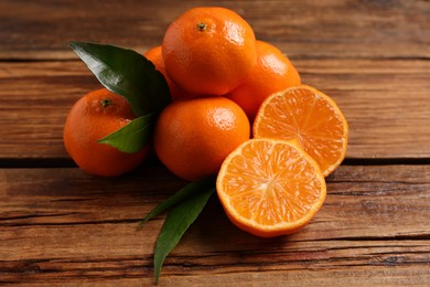 Photo of Fresh tangerines with green leaves on wooden table