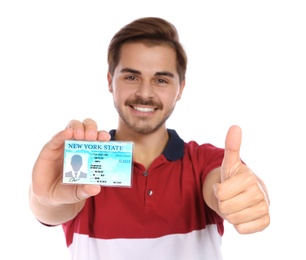 Happy young man with driving license on white background