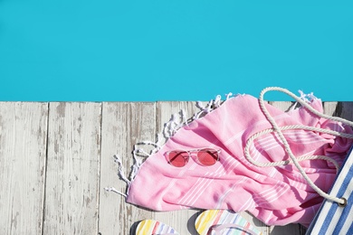 Beach accessories on wooden deck near outdoor swimming pool, flat lay. Space for text