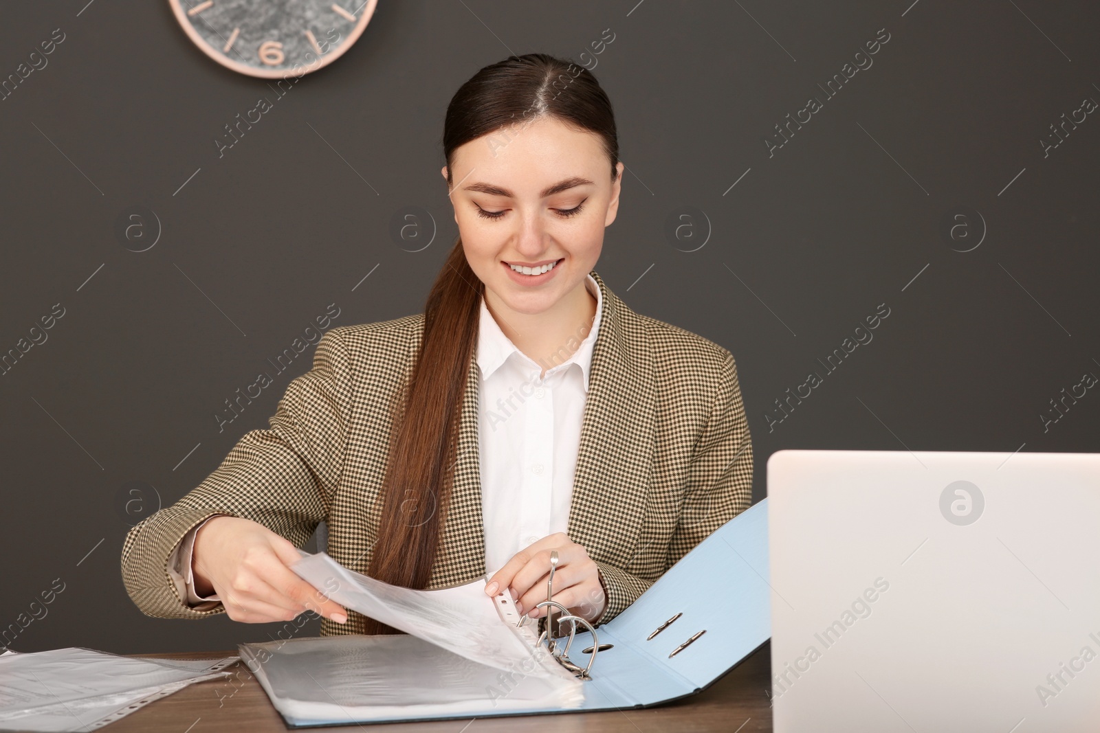 Photo of Businesswoman putting document into file folder at wooden table in office