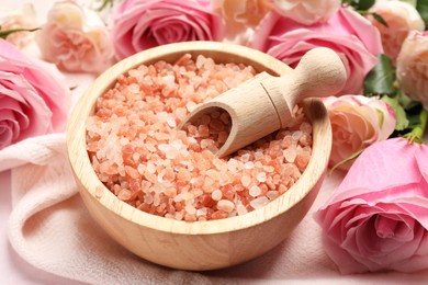 Photo of Aromatic sea salt and beautiful roses on beige cloth, closeup