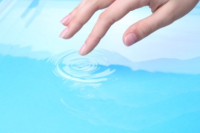 Photo of Woman touching clear water, closeup. Making ripples