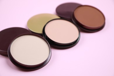 Photo of Different face powders on pink background, closeup. Space for text