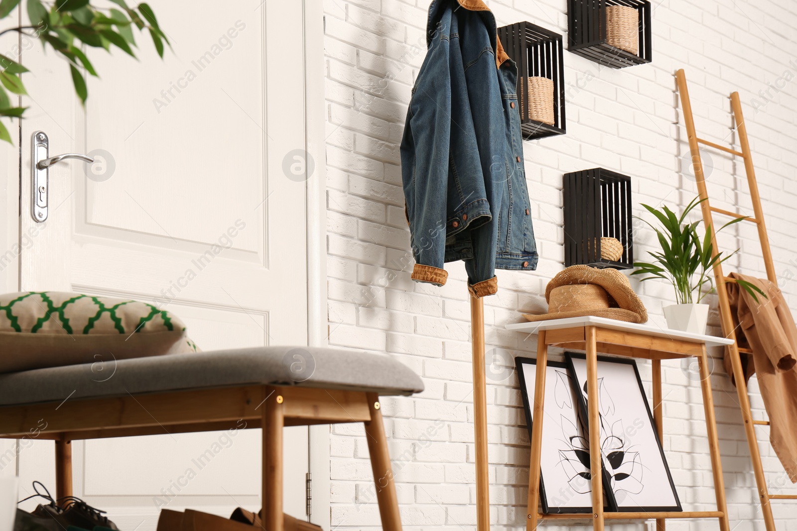 Photo of Stylish hallway interior with shoe storage bench, hanger stand and table