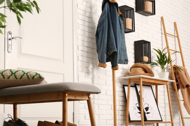 Stylish hallway interior with shoe storage bench, hanger stand and table