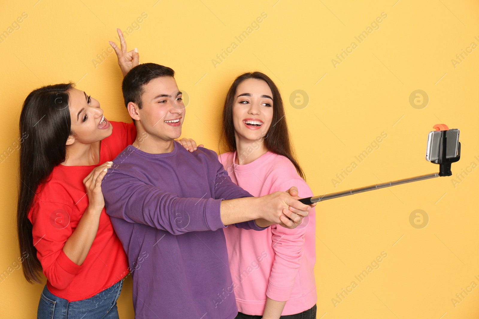 Photo of Young happy friends taking selfie against color background