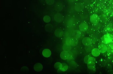 Image of St. Patrick day. Shiny green glitter on black background, bokeh effect