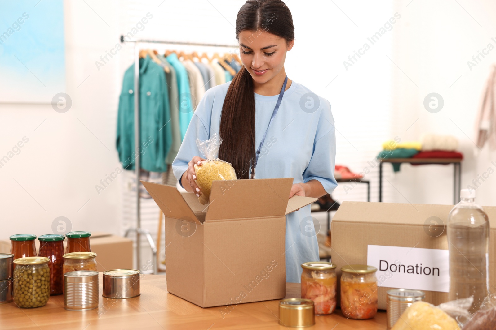 Photo of Volunteer packing food products at table in warehouse