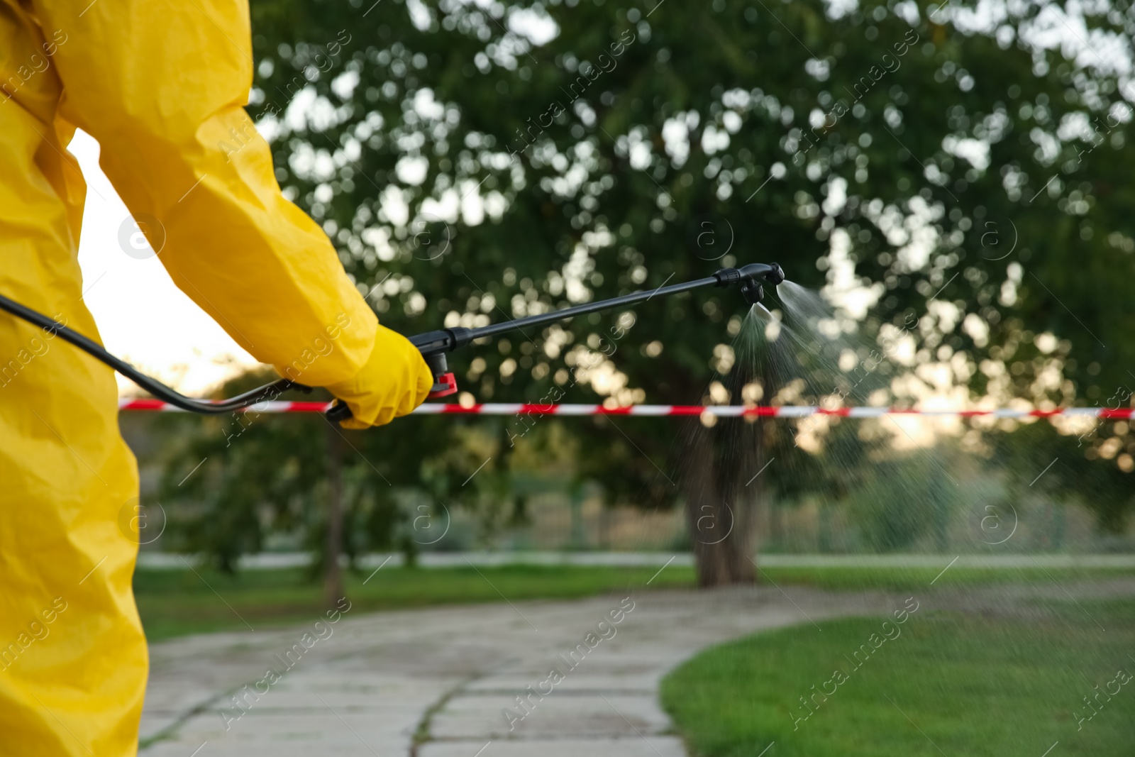 Photo of Person in hazmat suit disinfecting street with sprayer, closeup. Surface treatment during coronavirus pandemic