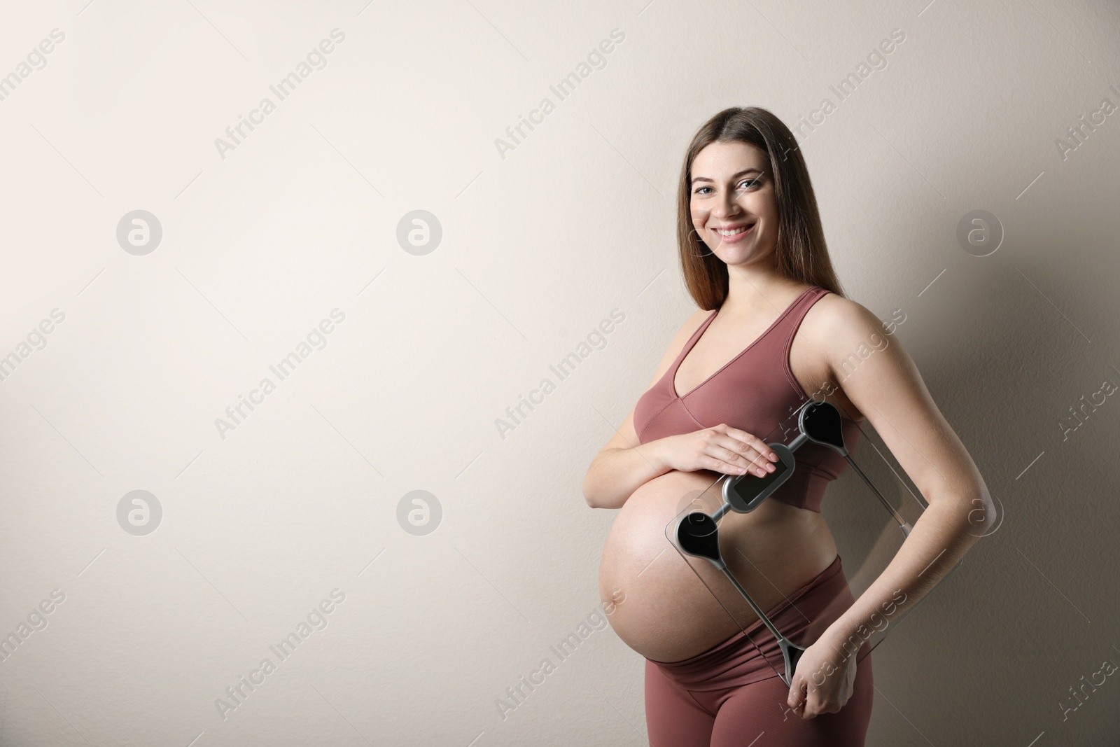 Photo of Pregnant woman with scales on beige background. Space for text