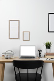 Photo of Cozy workspace with laptop and stationery on wooden desk at home