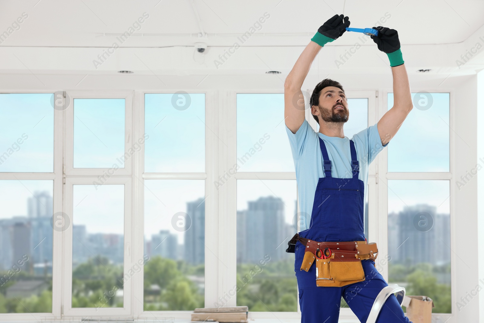 Photo of Electrician fixing wires with insulating tape indoors