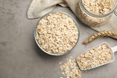 Photo of Oatmeal, glass bowl, jar and scoop on grey table, flat lay