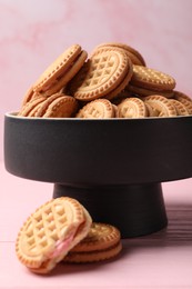 Tasty sandwich cookies with cream on pink wooden table, closeup