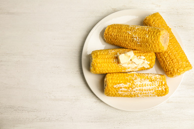 Photo of Delicious boiled corn with butter on white wooden table, top view. Space for text