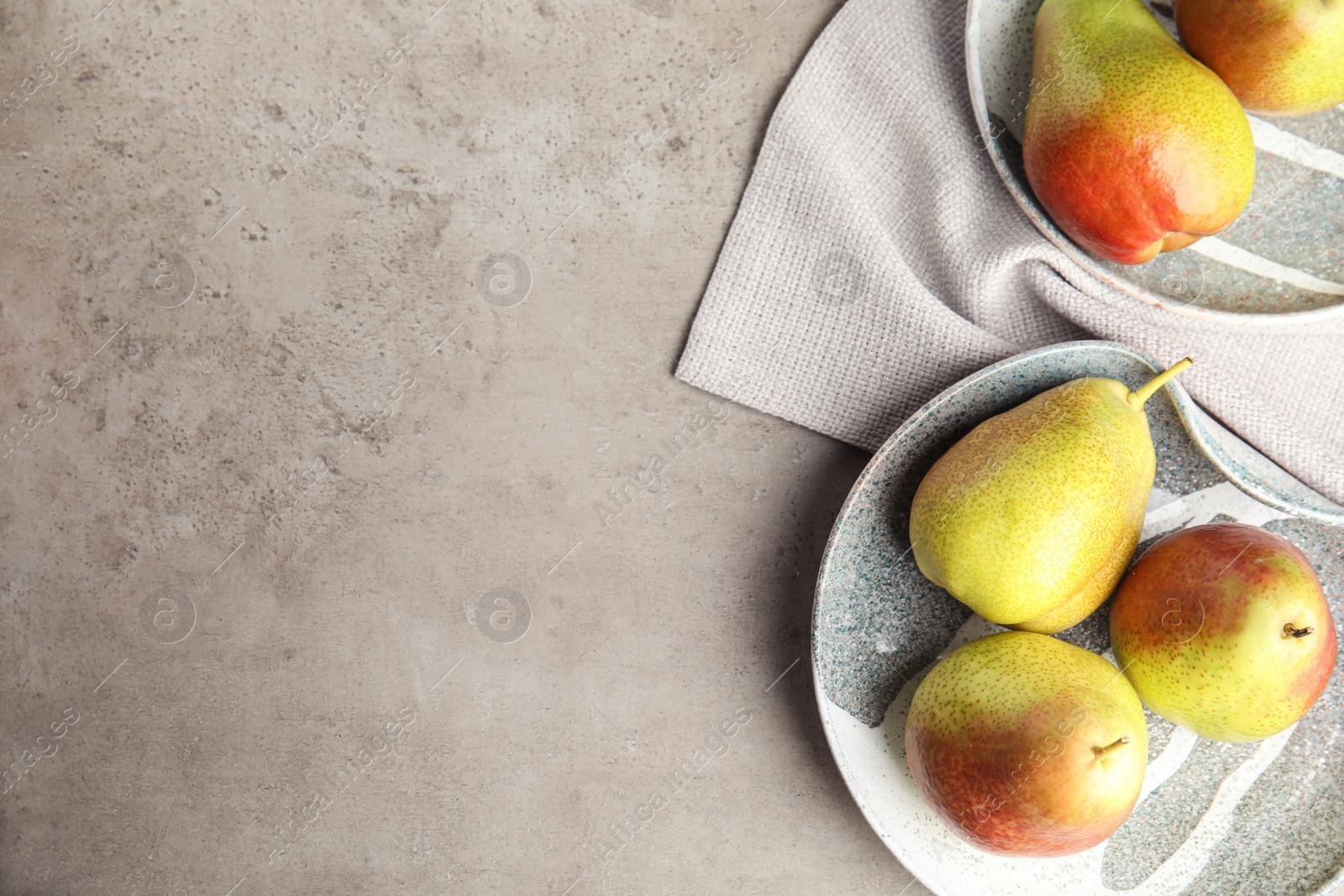 Photo of Plates with ripe juicy pears on grey stone table, flat lay. Space for text