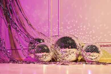 Photo of Shiny disco balls and foil fringe curtain indoors, color toned