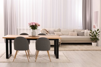 Photo of Table, chairs, sofa and vase with peonies in stylish dining room