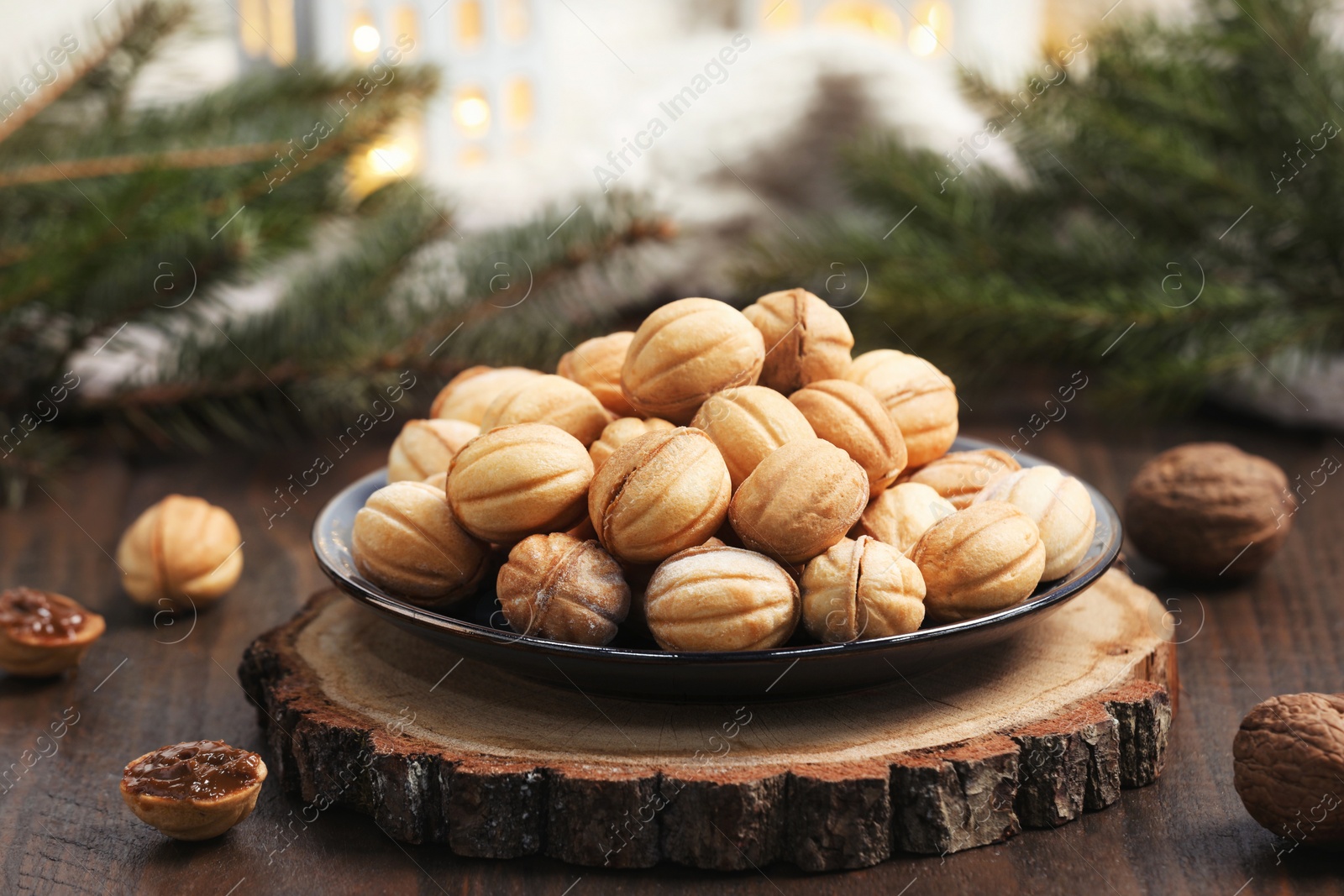 Photo of Homemade walnut shaped cookies with boiled condensed milk near fir branches on wooden table