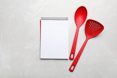 Different kitchen utensils and notebook on grey background, top view