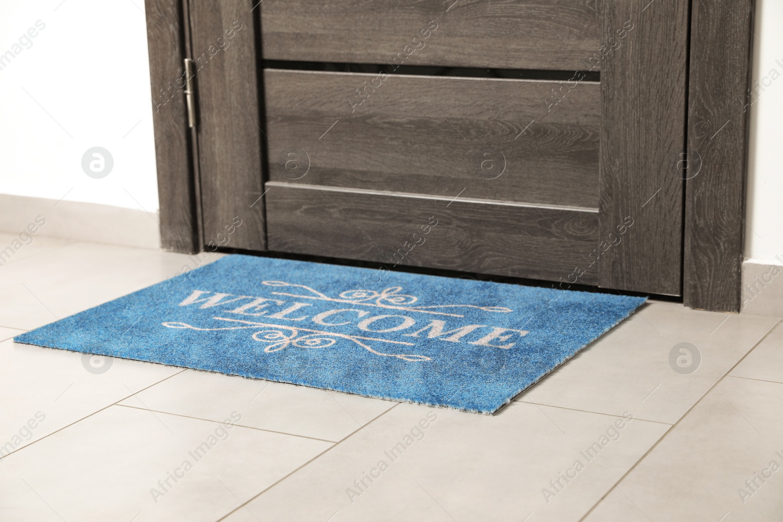 Photo of Beautiful doormat with word Welcome on floor near entrance