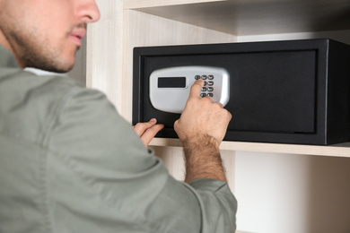 Man opening black steel safe with electronic lock at hotel, closeup