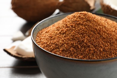 Natural coconut sugar in ceramic bowl on table, closeup