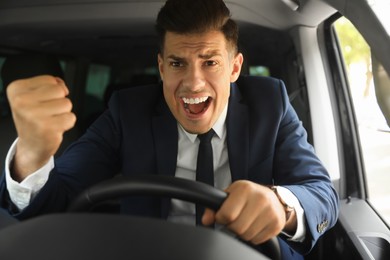Photo of Emotional man yelling in car. Aggressive driving behavior