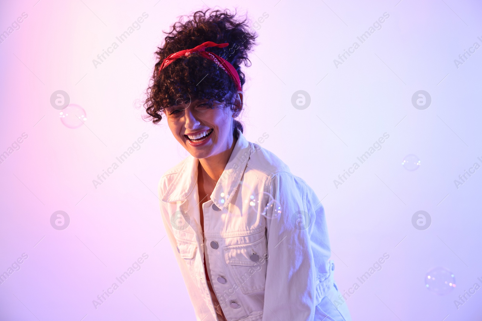 Photo of Beautiful young woman and bubbles on color background in neon lights