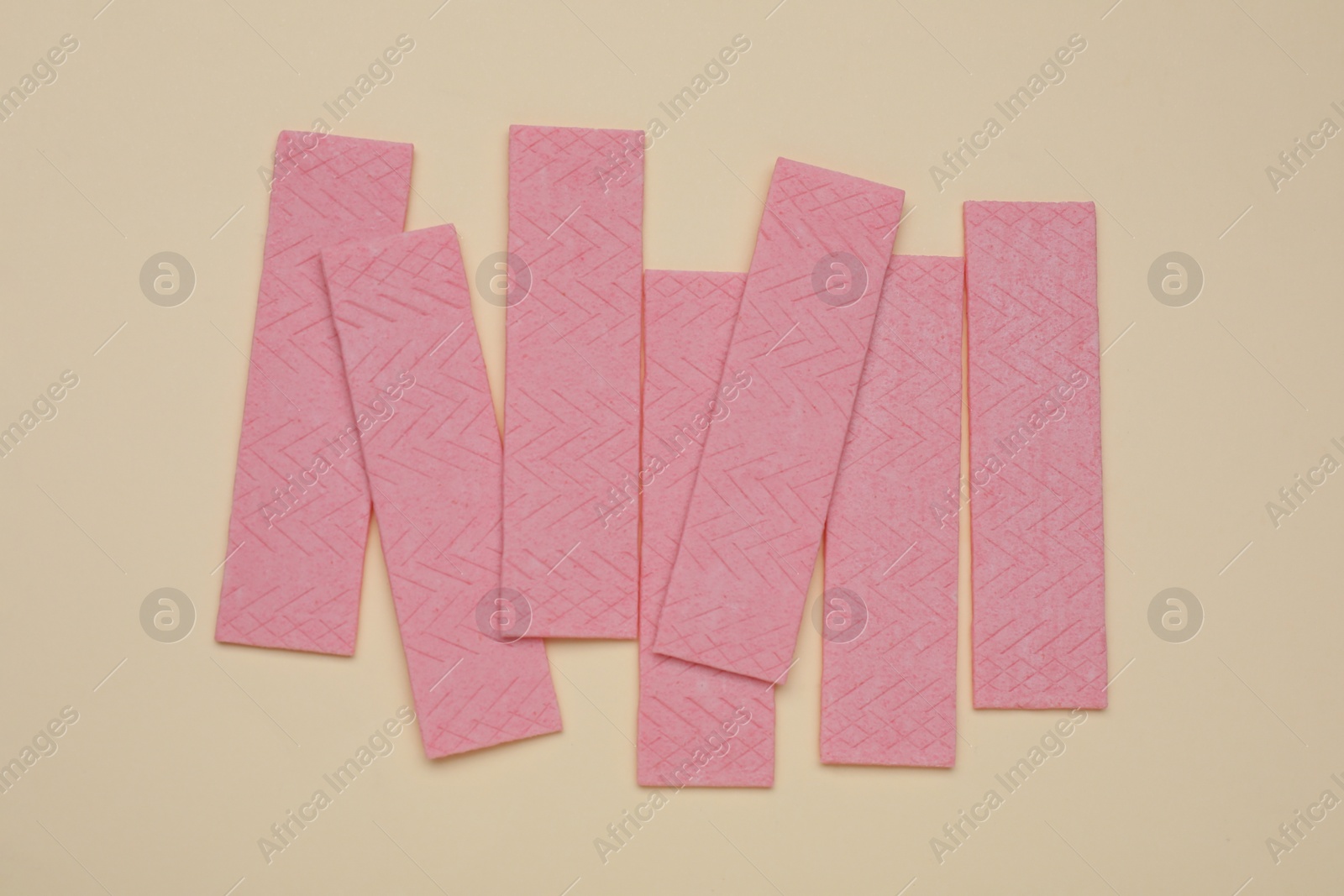 Photo of Sticks of tasty chewing gum on beige background, flat lay