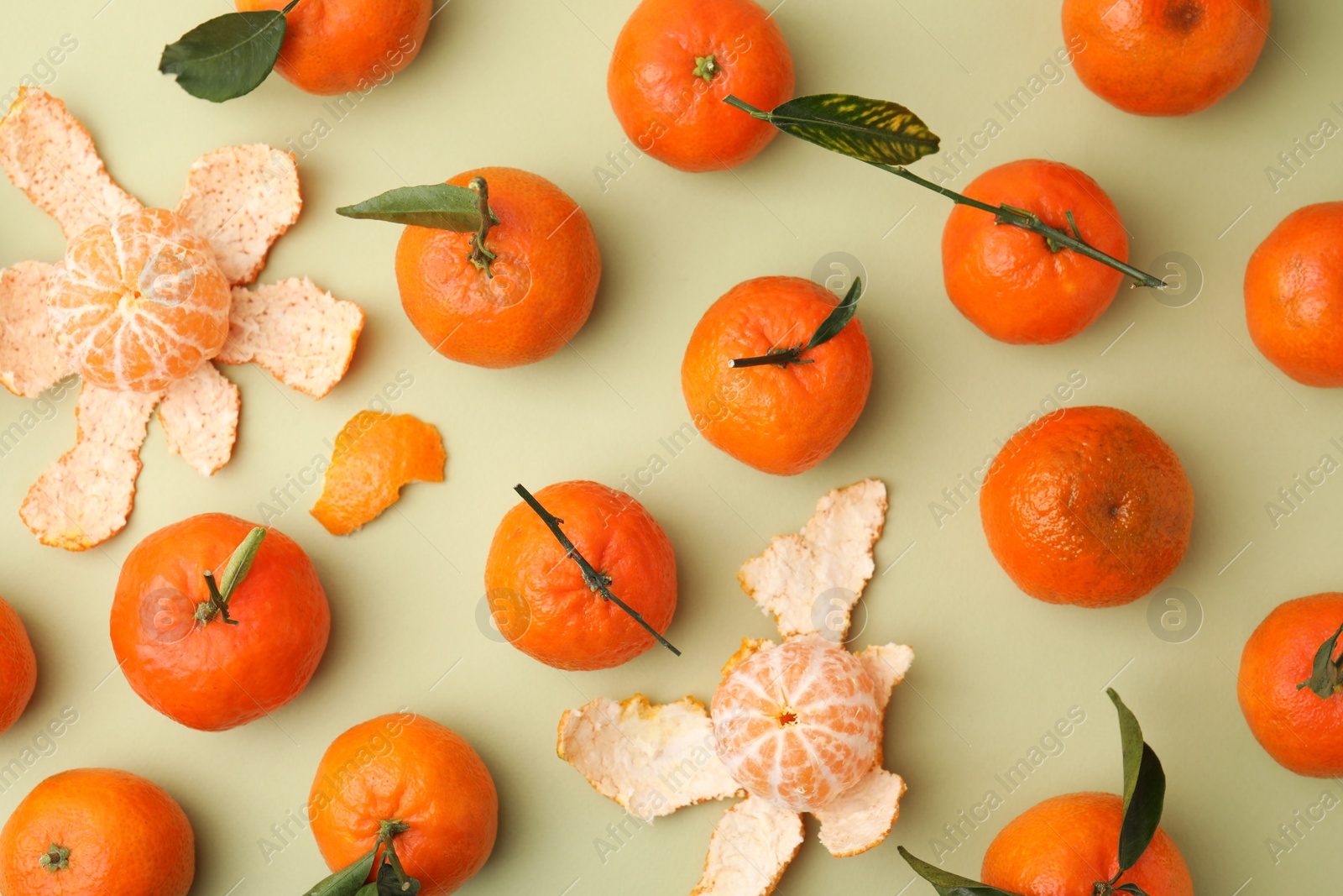 Photo of Many fresh ripe tangerines and leaves on light green table, flat lay