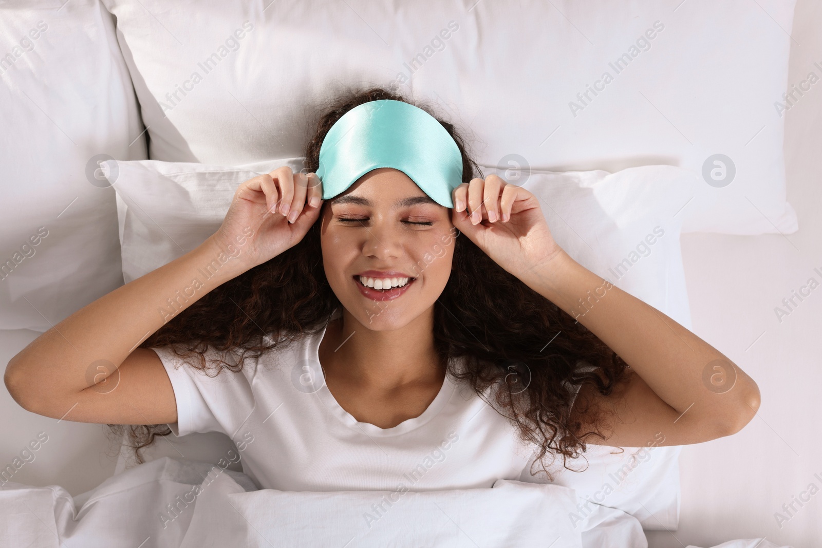 Photo of Happy African American woman with sleeping mask in bed, top view