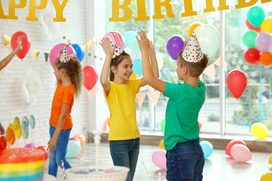 Happy children playing at birthday party in decorated room