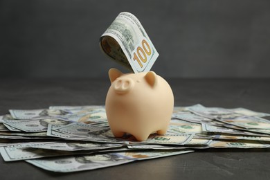 Photo of Money exchange. Dollar banknotes and piggy bank on dark gray textured background