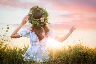 Young woman wearing wreath made of beautiful flowers outdoors on sunny day, back view