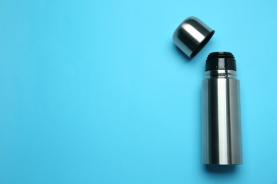 Stainless steel thermos on light blue background, top view. Space for text