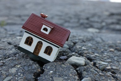 Photo of House model in cracked asphalt. Earthquake disaster
