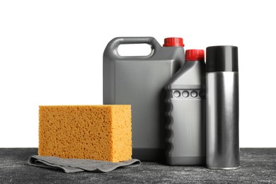 Bottles, cloth and car wash sponge on black table against white background