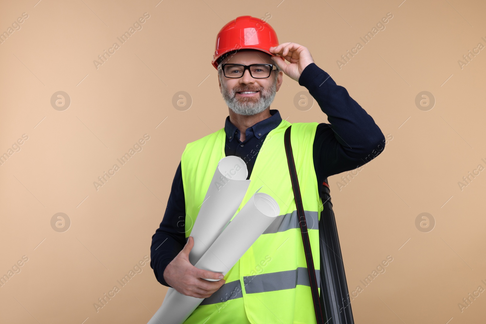 Photo of Architect in hard hat holding drafts on beige background
