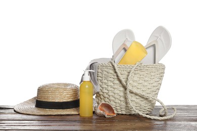 Stylish bag, skin care products and beach accessories on wooden table against white background