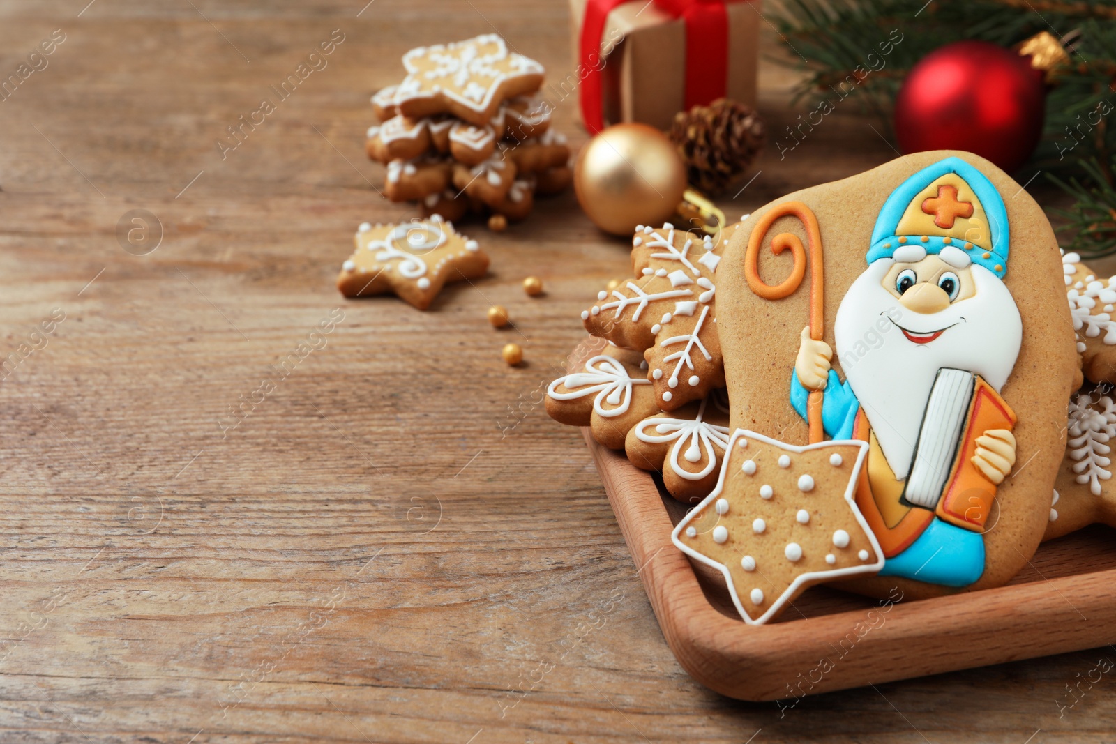 Photo of Tasty gingerbread cookies and festive decor on wooden table, space for text. St. Nicholas Day celebration