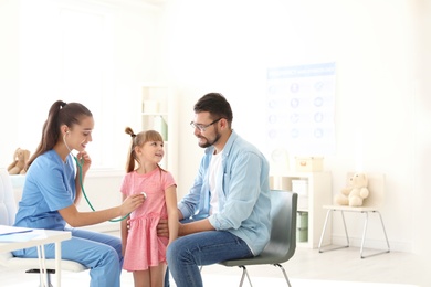 Photo of Children's doctor examining little girl with stethoscope in hospital. Space for text