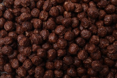 Tasty chocolate cereal balls as background, top view