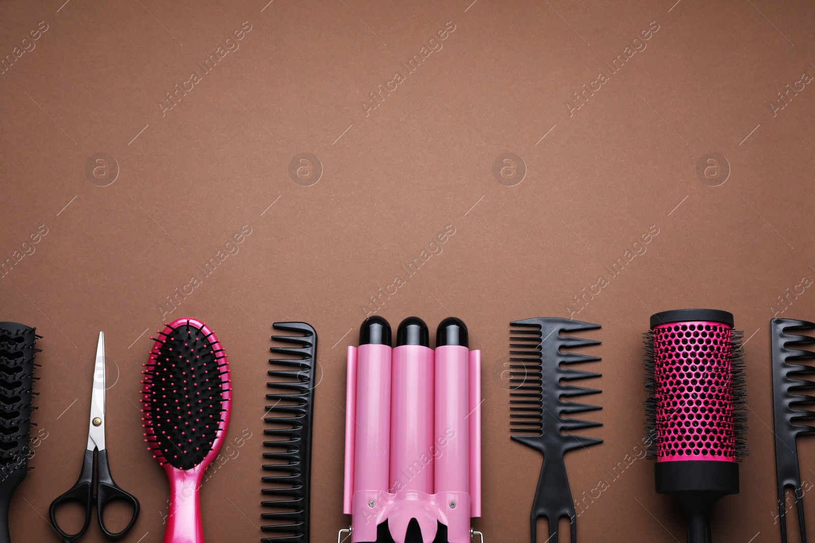 Photo of Flat lay composition of professional hairdresser tools on brown background, space for text