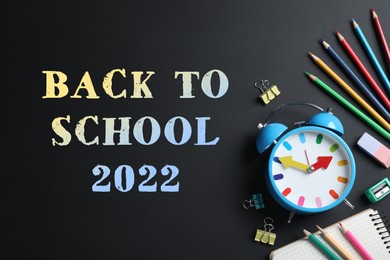 Back to school 2022. Flat lay composition with alarm clock and different stationery on black background