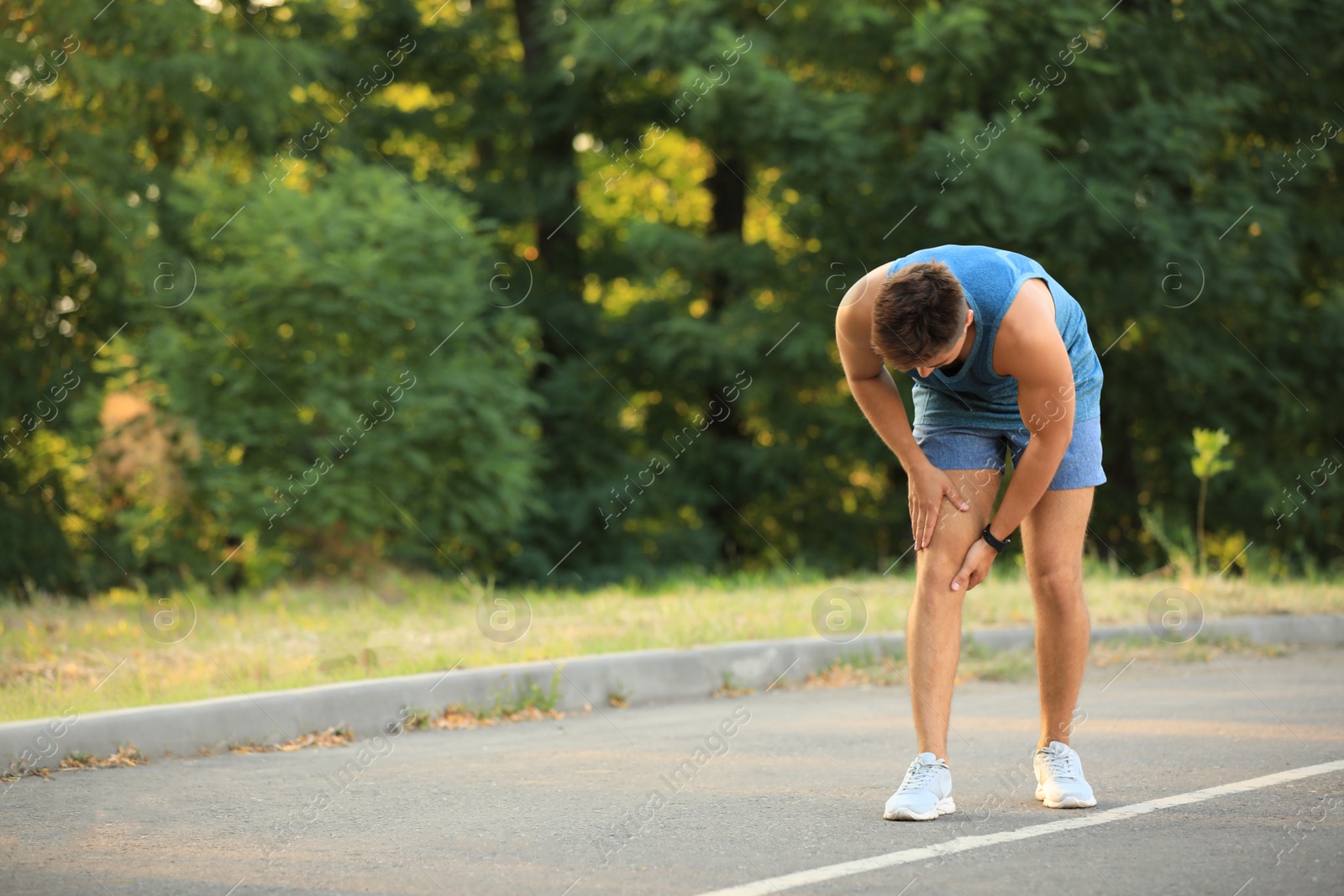 Photo of Young man in sportswear having knee problems in park